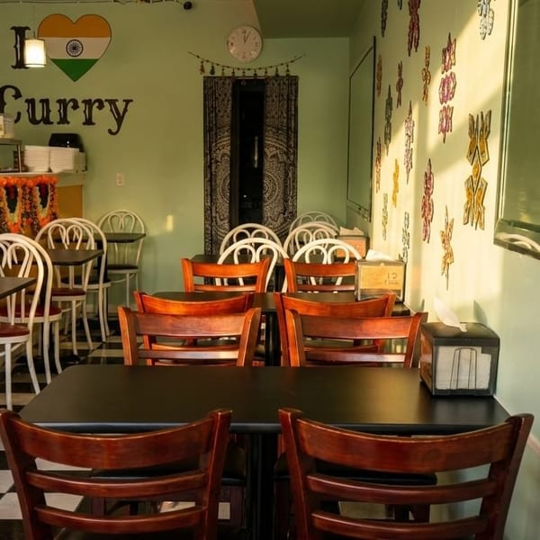 Empty dining room with black and white checkered floor, light green walls, and "I love Curry" sign.